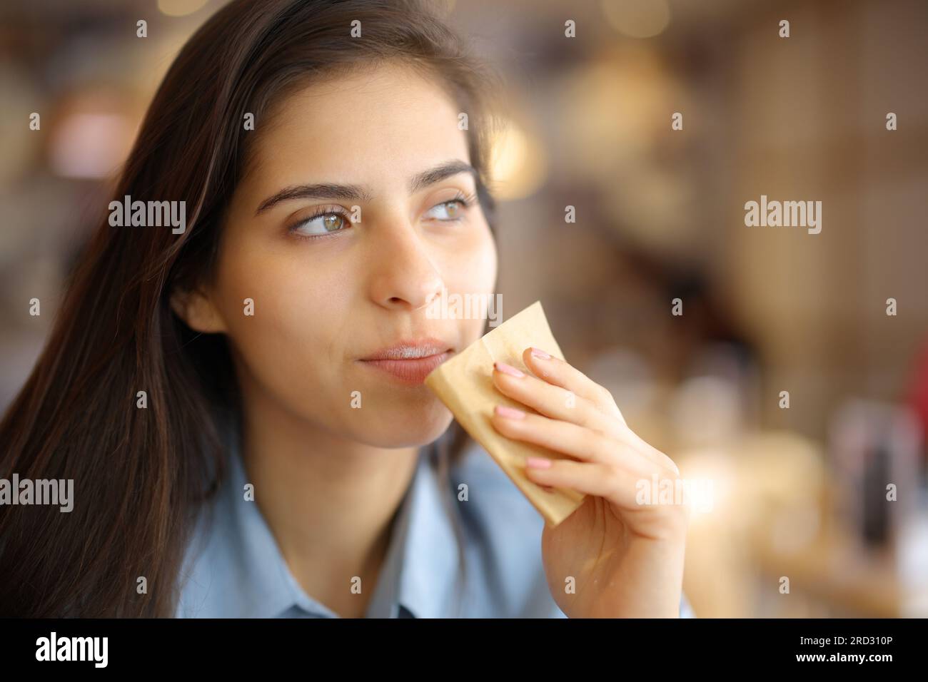 Cliente del restaurante que limpia la boca con papel de seda mirando hacia otro lado Foto de stock