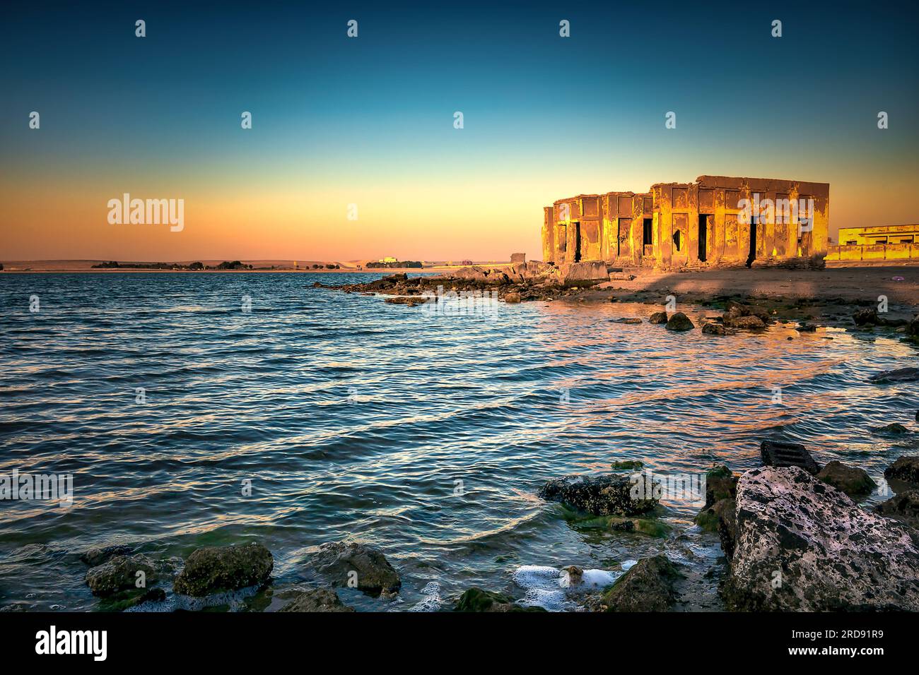 Amanecer impresionante con vista en agua sedosa Al uqair arruinado fort, al lado del mar de Arabia Saudita. Foto de stock