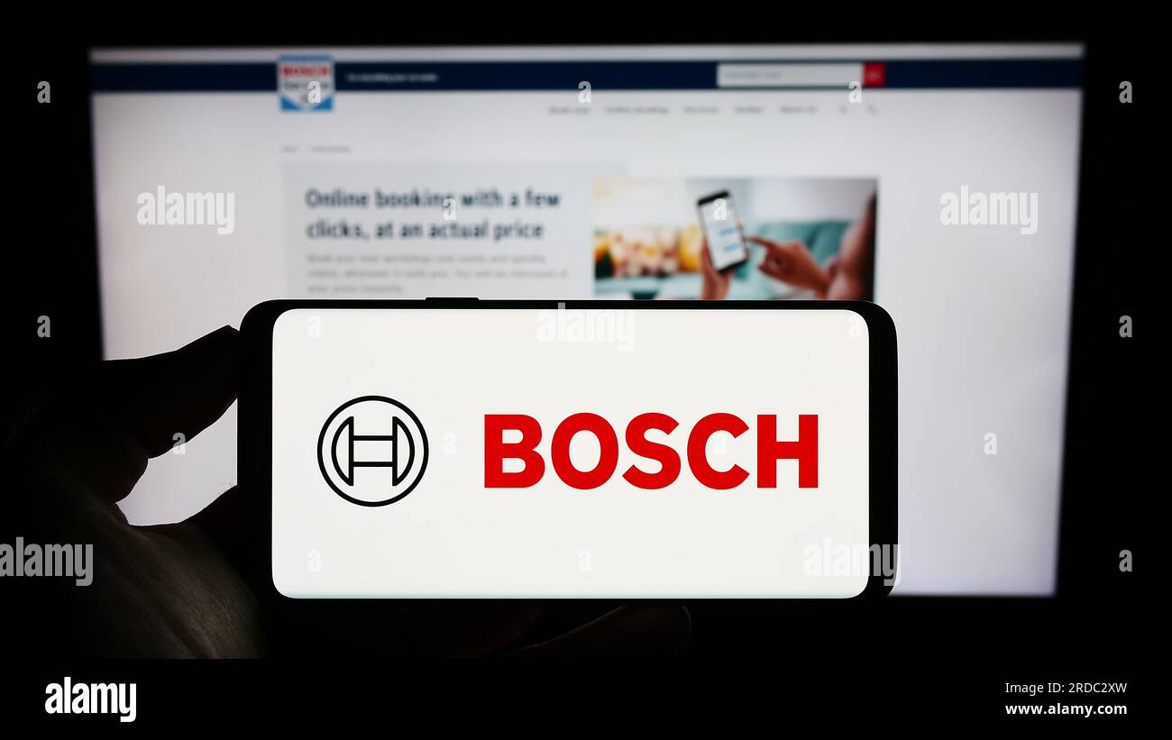 Persona que sostiene el teléfono móvil con el logotipo de la empresa de ingeniería alemana Robert Bosch GmbH en la pantalla delante de la página web. Enfoque en la pantalla del teléfono. Foto de stock