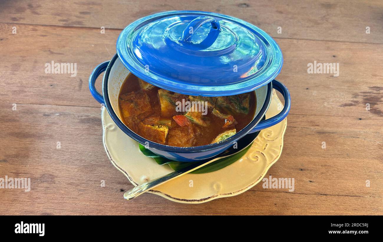 Curry de estilo tailandés con huevo cocido en olla azul sobre mesa de madera Foto de stock
