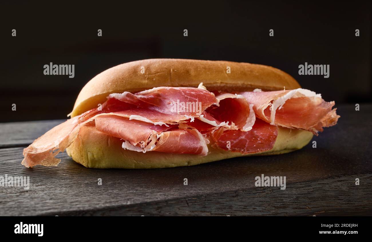 sándwich con lonchas de jamón ibérico español sobre tabla de madera