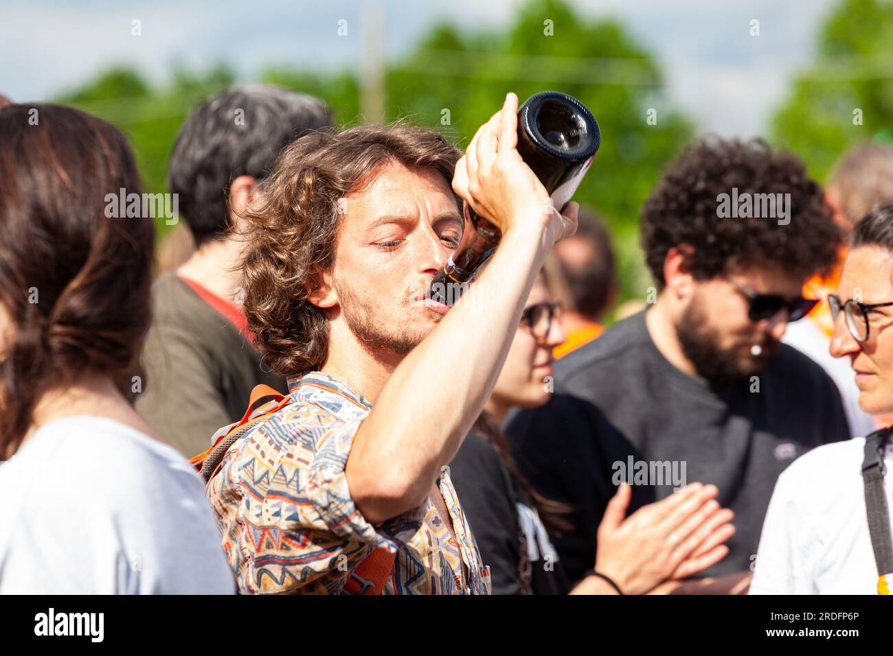 Gattatico, Reggio Emilia, Italia - 25 de abril de 2023: Amigos felices bebiendo vino de la botella en el concierto del Día de la Liberación de Italia. Foto de stock