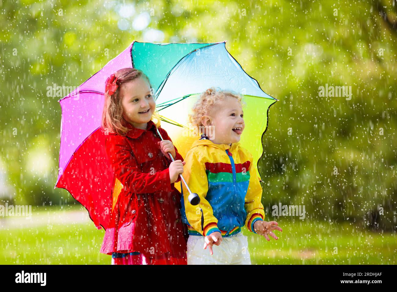 Niño Con Paraguas De Colores, Vestido Con Capa Impermeable Amarilla Y Botas  De Pie Bajo La Lluvia. Niño Caminando En La Ducha De Otoño. Fotos,  retratos, imágenes y fotografía de archivo libres