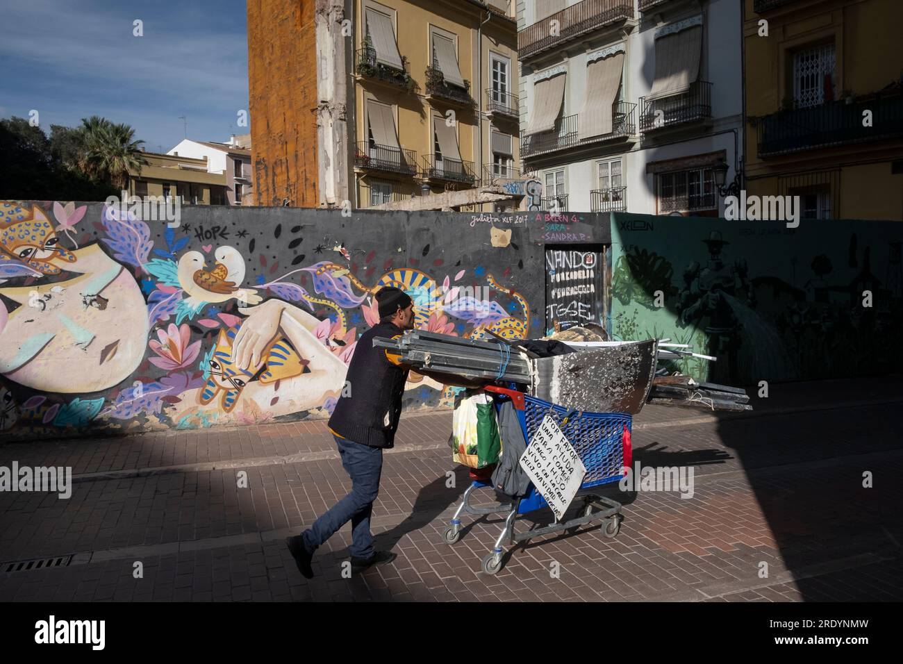 Obdachloser mit seinem Hab und gut vor Street Art in der Altstadt von Valencia *** Hombre sin hogar con sus pertenencias frente al arte callejero en el viejo Foto de stock