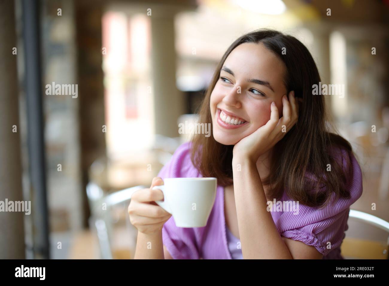 Mujer soñadora bebiendo café y soñando en una terraza de bar Foto de stock