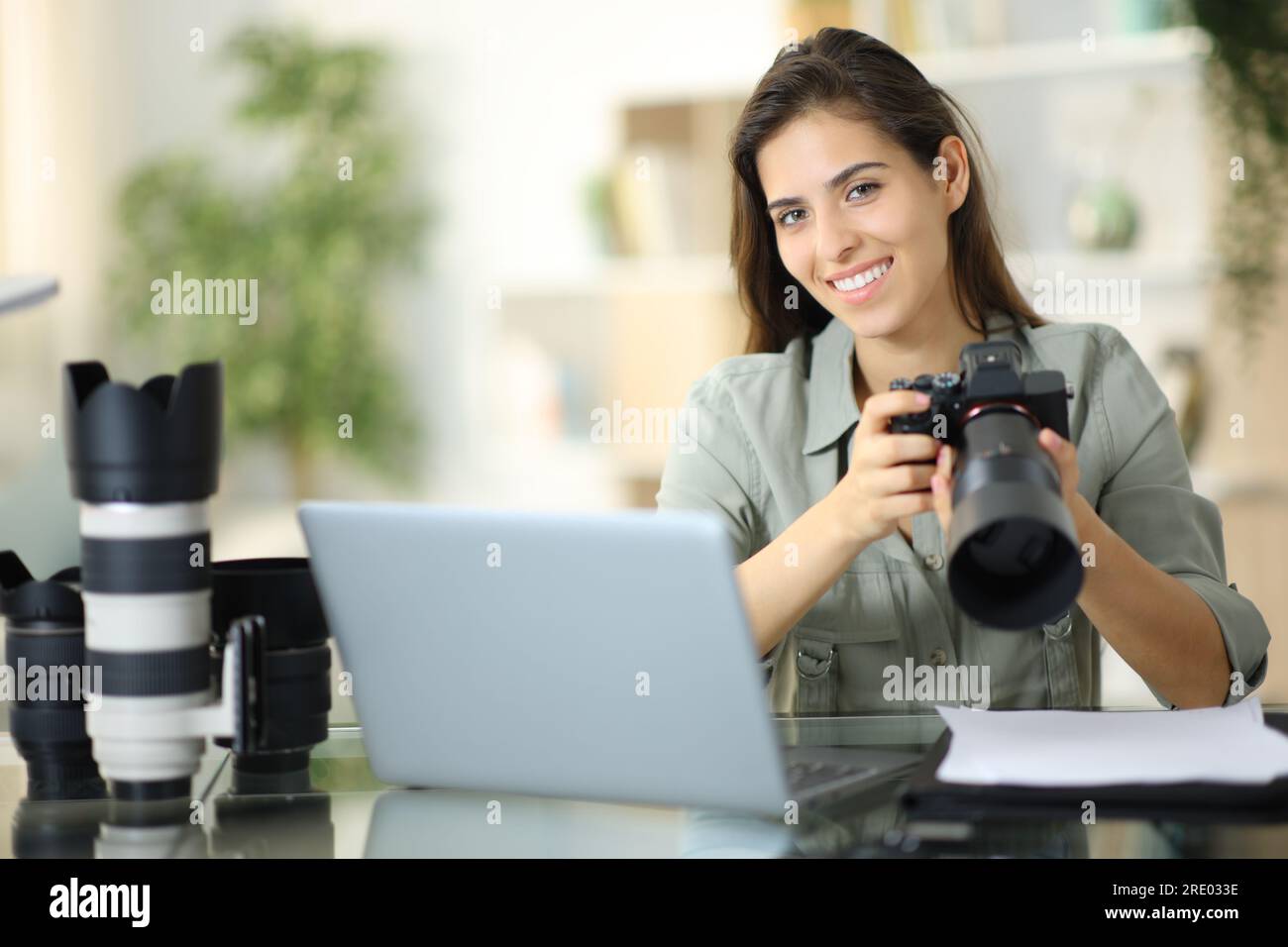 Fotógrafa feliz posando en casa mirándote con su equipo Foto de stock