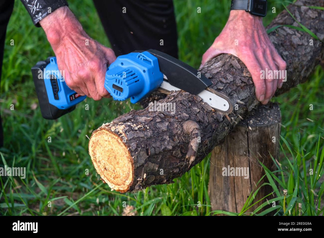 Sierra eléctrica portátil portátil portátil de mano en una batería para  cortar leña y madera. Primer plano, una mano aserrando un tronco, astillas  volando Fotografía de stock - Alamy