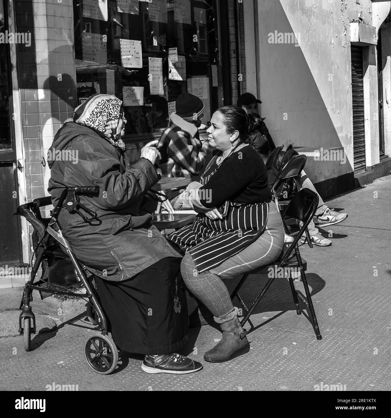 mujer joven y vieja hablando escena de la calle Foto de stock