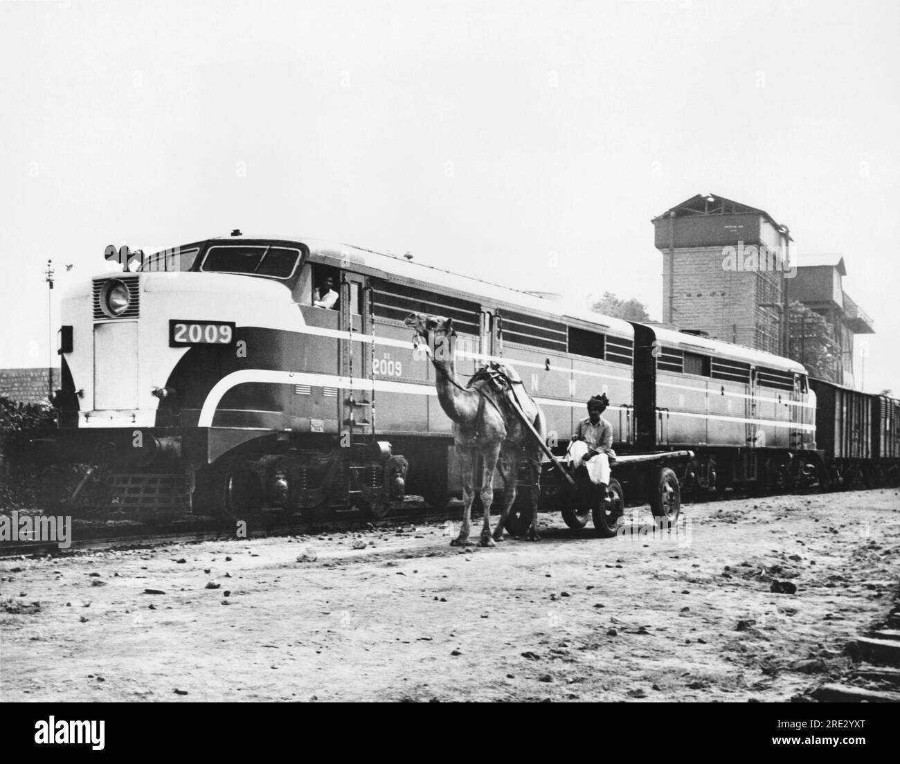 Pakistán: 1952 Un camello y un ingeniero de trenes son el viejo y nuevo transporte en Pakistán. Los motores del ferrocarril fueron comprados con préstamos del Banco Mundial, y el camello ya tenía el carro. Foto de stock