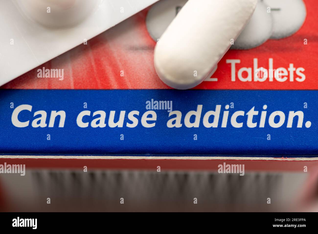 Un concepto de adicción médica con una caja de medicamento que contiene opioides y la advertencia de que puede causar adicción. Foto de stock