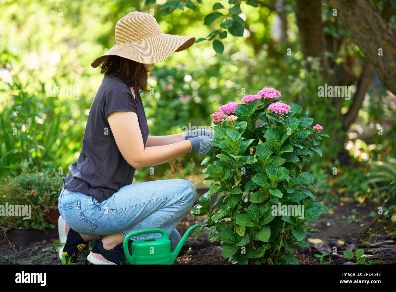 Jardinero mujer en sombrero y guantes plantas flores en el jardín