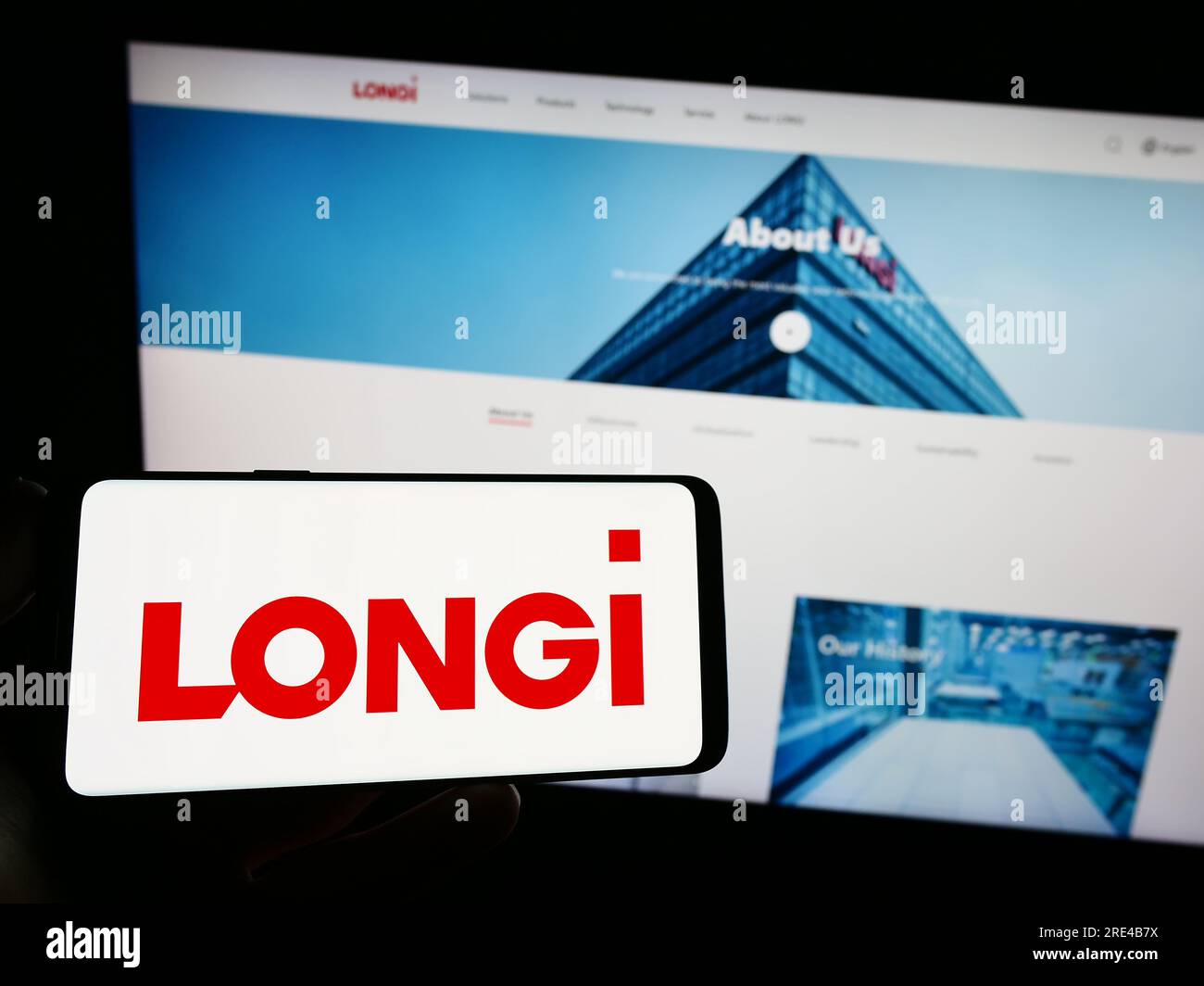 Persona que sostiene el teléfono inteligente con el logotipo de la compañía longi Green Energy Technology Co. Ltd. En la pantalla delante del sitio web. Enfoque en la pantalla del teléfono. Foto de stock