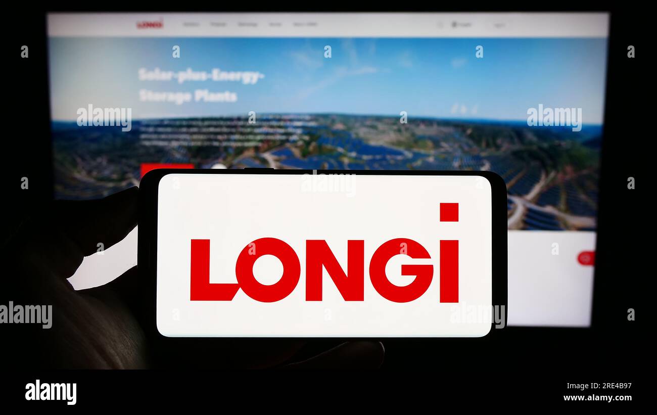 Persona que sostiene el teléfono móvil con el logotipo de la compañía longi Green Energy Technology Co. Ltd. En la pantalla delante de la página web. Enfoque en la pantalla del teléfono. Foto de stock