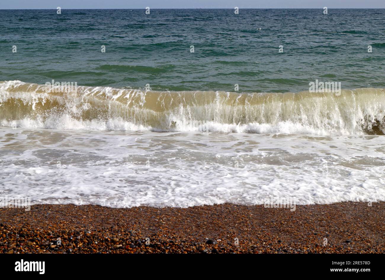 Una ola rompiendo en la orilla del mar de un mar moderado en verano en la costa norte de Norfolk en Cley Next the Sea, Norfolk, Inglaterra, Reino Unido. Foto de stock