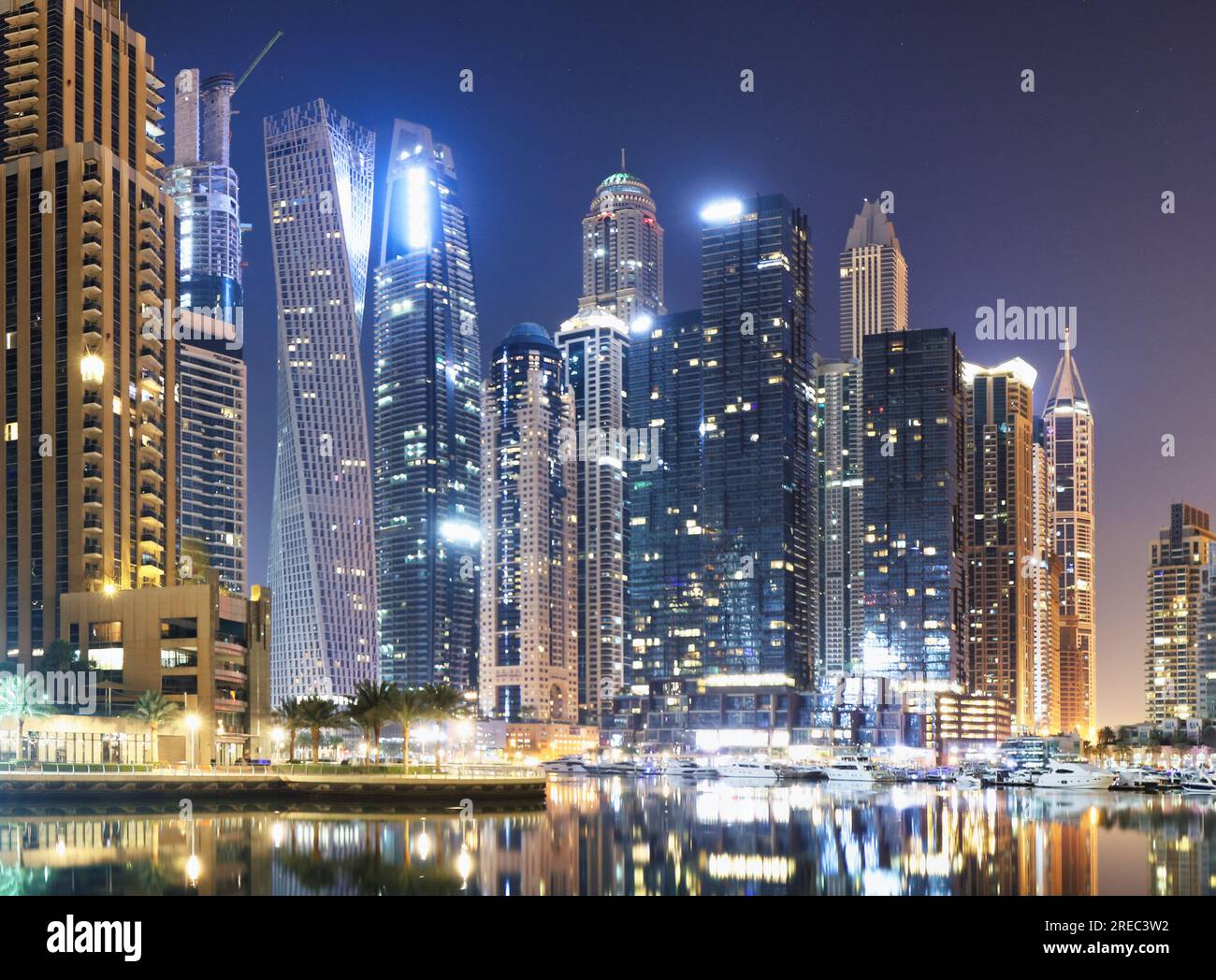 Paseo marítimo y canal en Dubai Marina por la noche con rascacielos de lujo alrededor, Emiratos Árabes Unidos Foto de stock