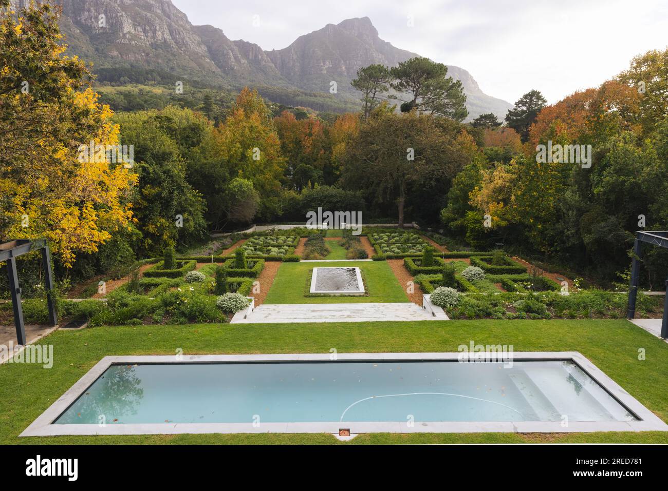 Vista general del hermoso jardín casero con piscina y árboles cerca del paisaje de las montañas Foto de stock