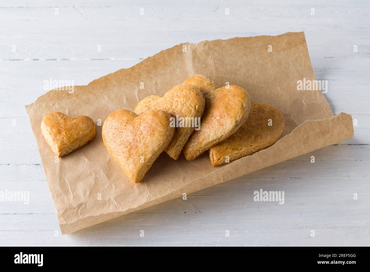 Galletas de pan corto en forma de corazón en papel artesanal sobre un fondo azul claro. día de la cookie. Foto de stock