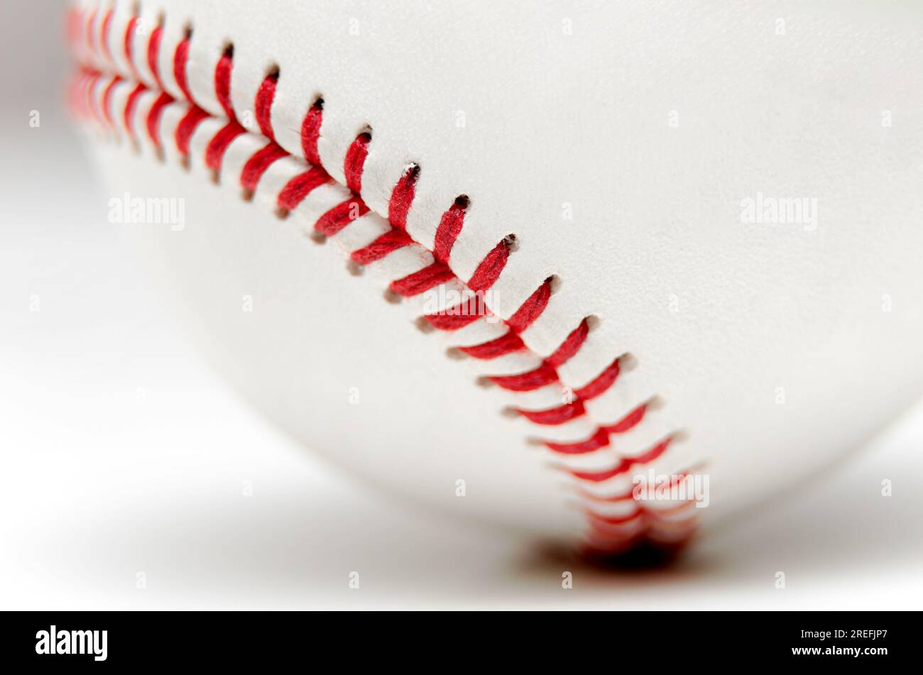 Primer plano de una pelota de béisbol blanca con puntos rojos sobre un fondo blanco Foto de stock