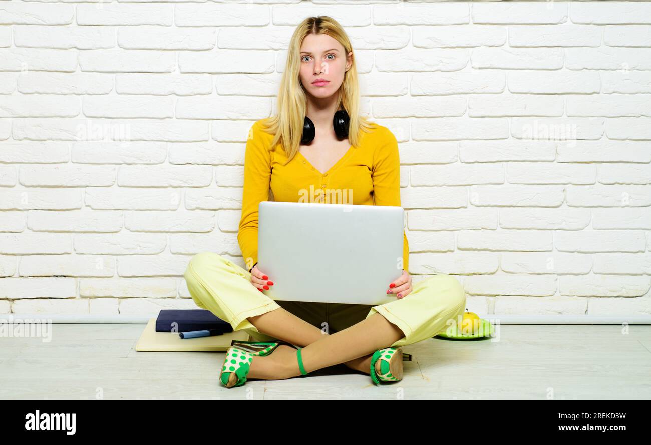 E-learning. Estudiante femenina seria sentada en el piso con las piernas cruzadas estudiando online en casa. Escuela secundaria. Estudiante universitaria chica preparándose para el examen Foto de stock