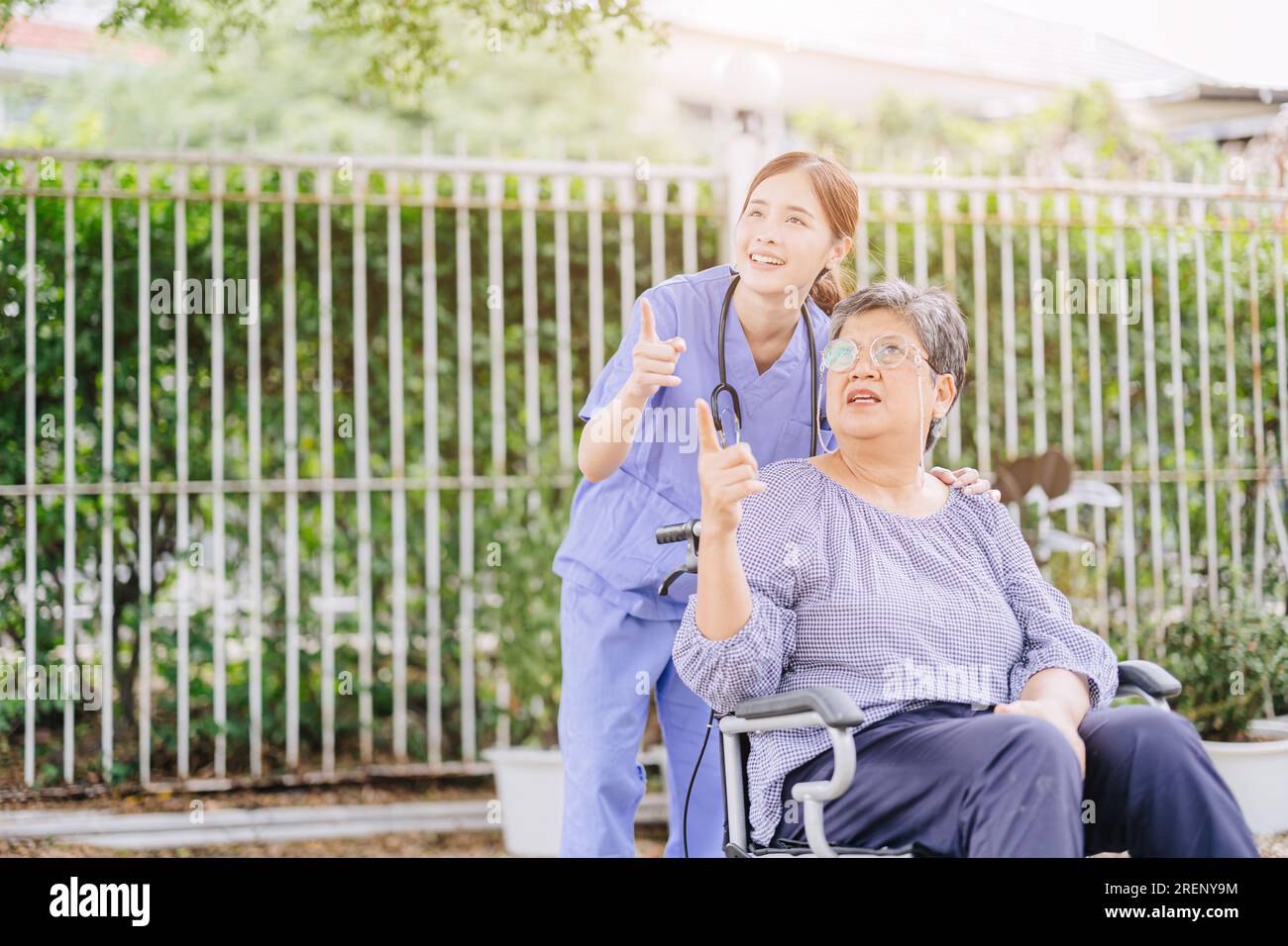 la mujer adulta mayor con silla de ruedas de la discapacidad en el hogar enfermera médico o fisioterapeuta ayuda a relajarse al aire libre Foto de stock