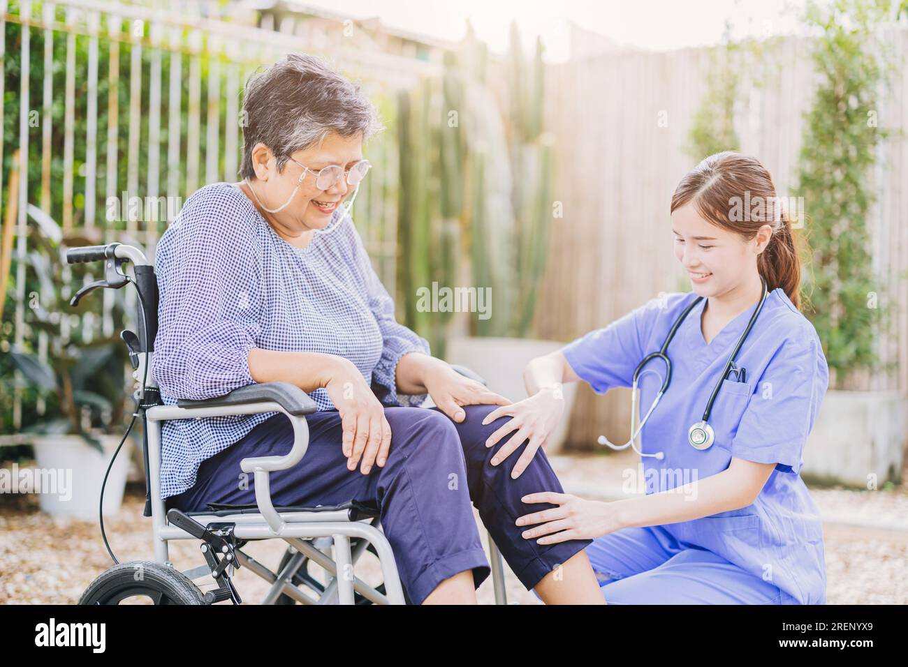 la mujer adulta mayor con silla de ruedas de la discapacidad en el hogar enfermera médico o fisioterapeuta ayuda a relajarse al aire libre Foto de stock