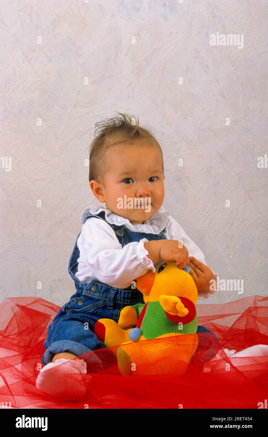 Bebé de 4 meses de edad sentado con los pies descalzos sobre una alfombra.  Juguetes en primer plano Fotografía de stock - Alamy