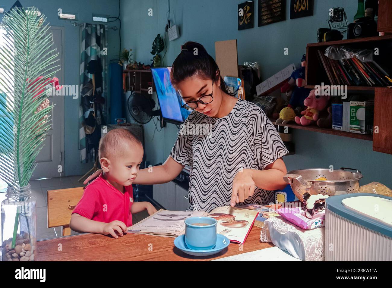 Madre y sus niños pequeños mirando un libro de imágenes juntos Foto de stock