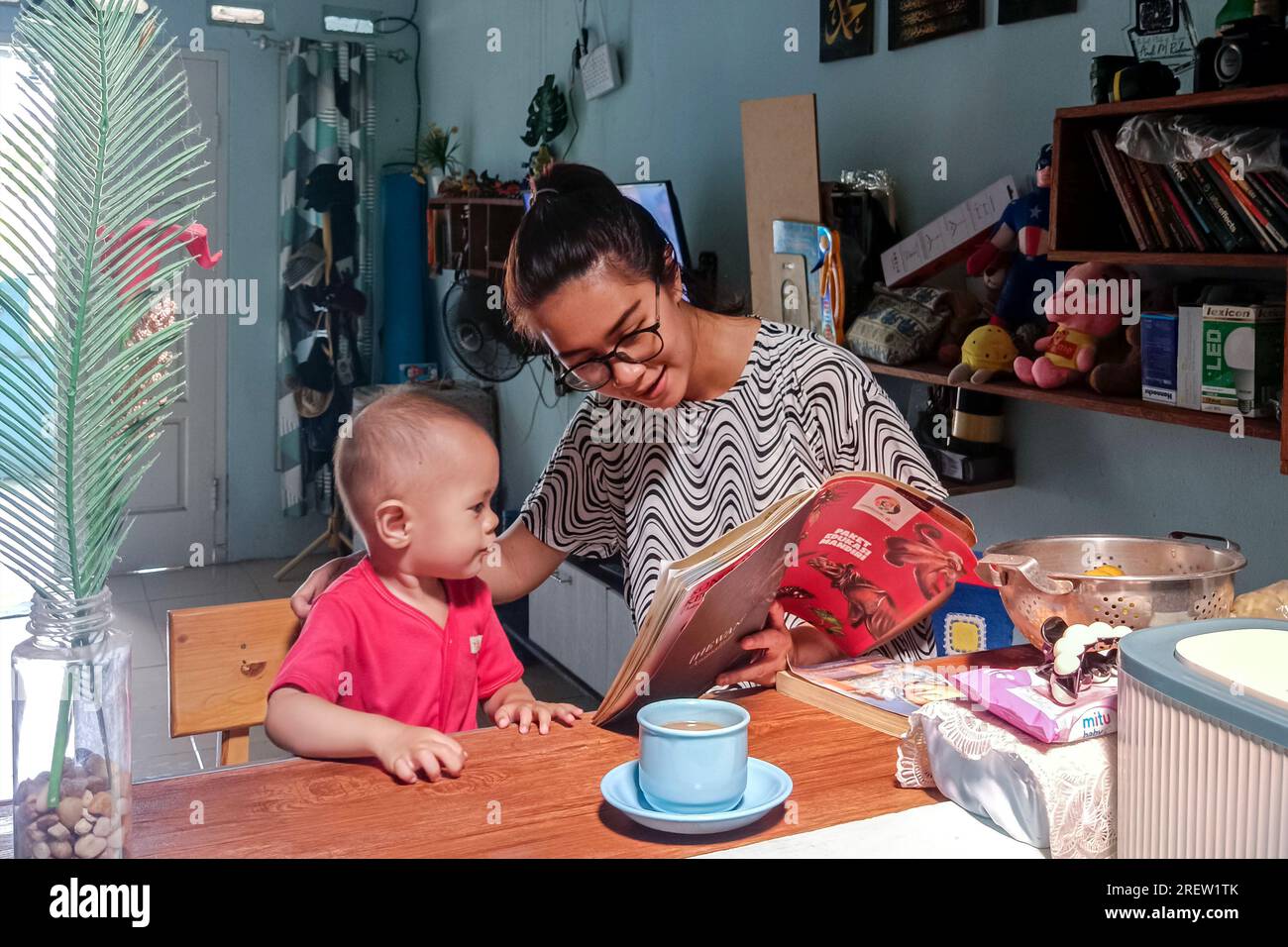 Madre y sus niños pequeños mirando un libro de imágenes juntos Foto de stock