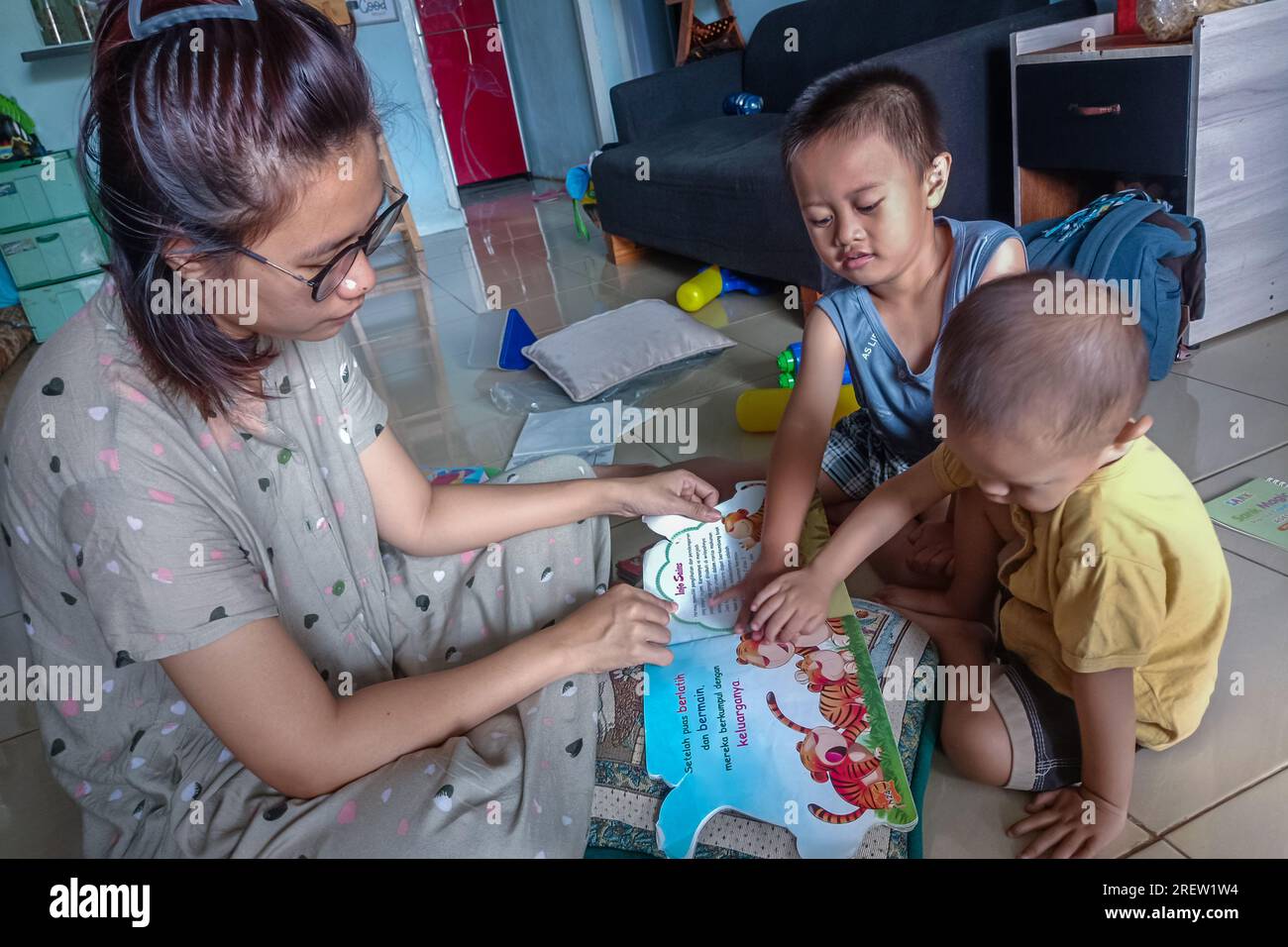 Madre y sus niños pequeños mirando un libro de imágenes juntos Foto de stock