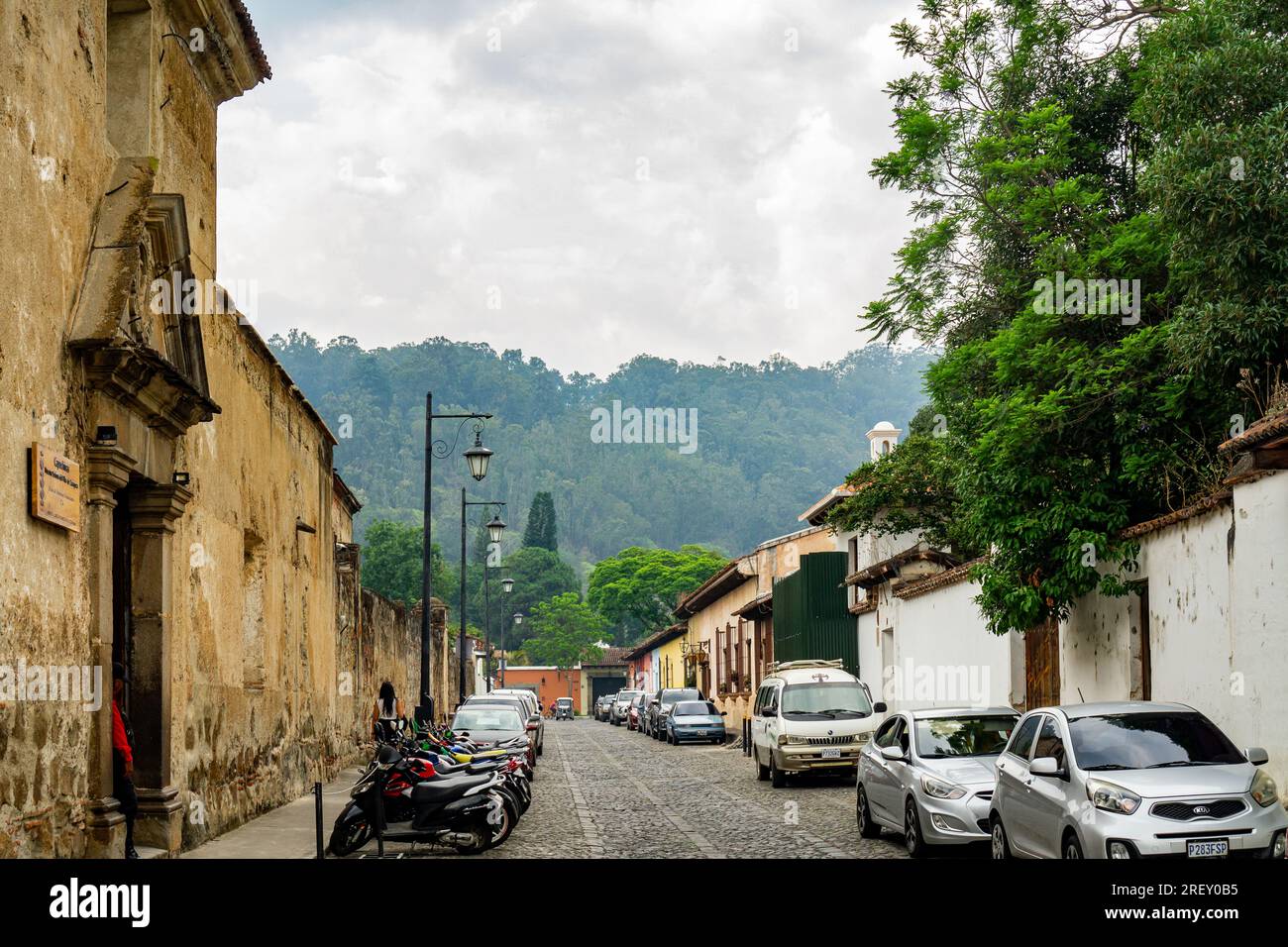 Antigua, Guatemala- 22 de mayo de 2023: Disminución de la perspectiva de la calle guatemalteca de Antigua con carretera adoquinada y autos estacionados en el costado Foto de stock