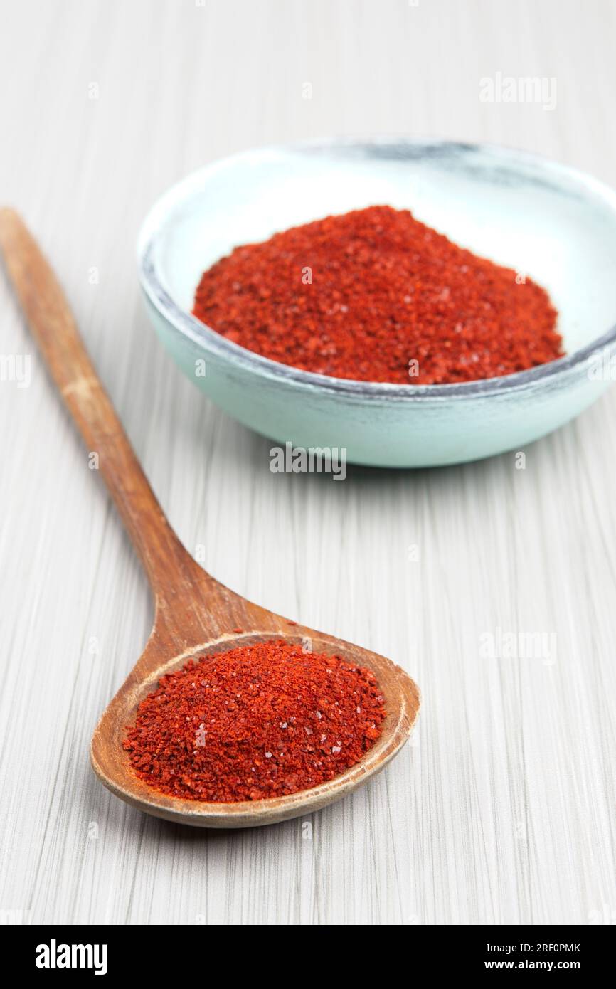 Foto de estudio de polvo de pimienta roja en una cuchara de madera con un tazón de madera de polvo de pimienta. Foto de stock