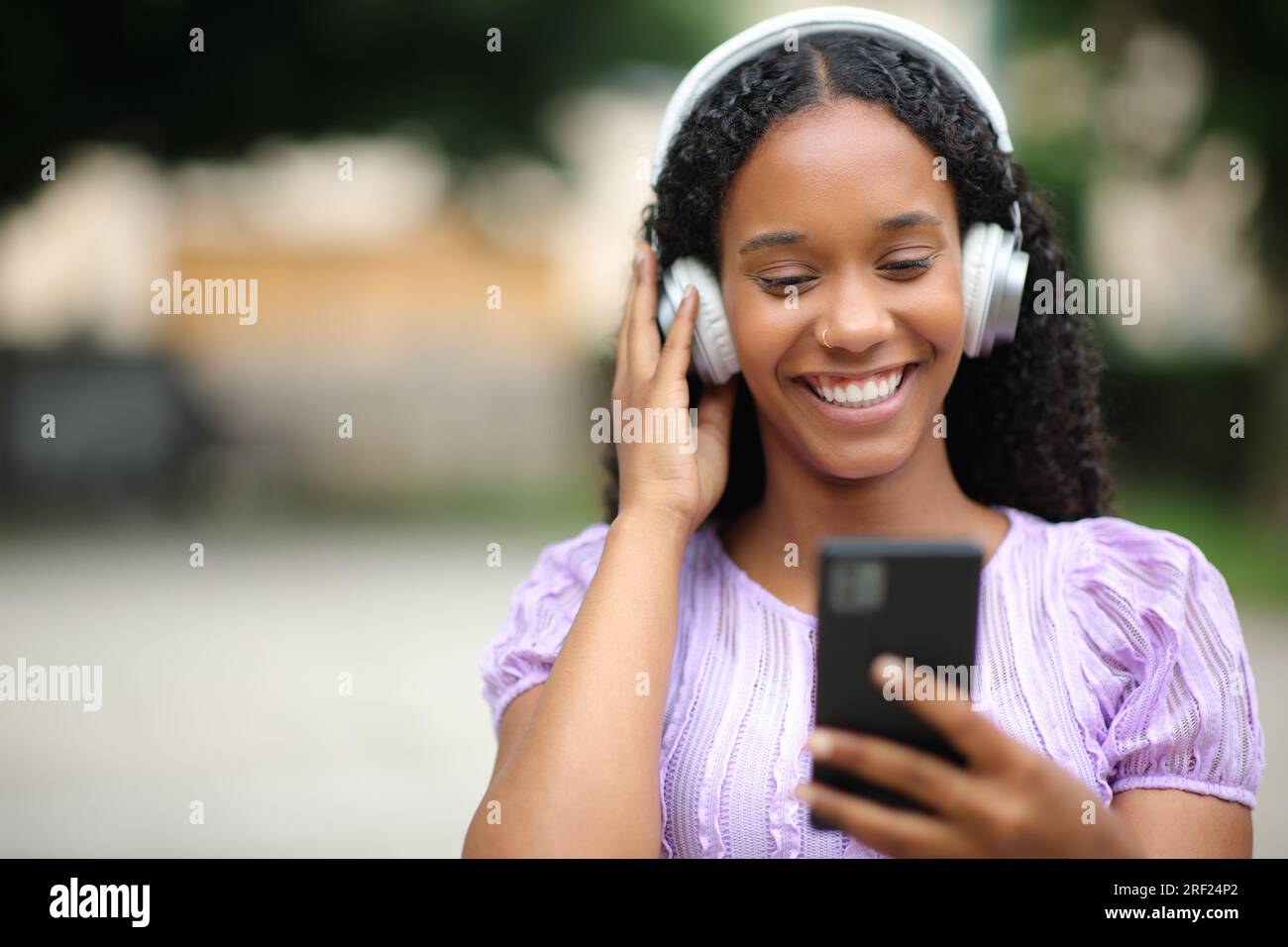 Retrato de la vista frontal de una mujer negra feliz escuchando música en la calle Foto de stock