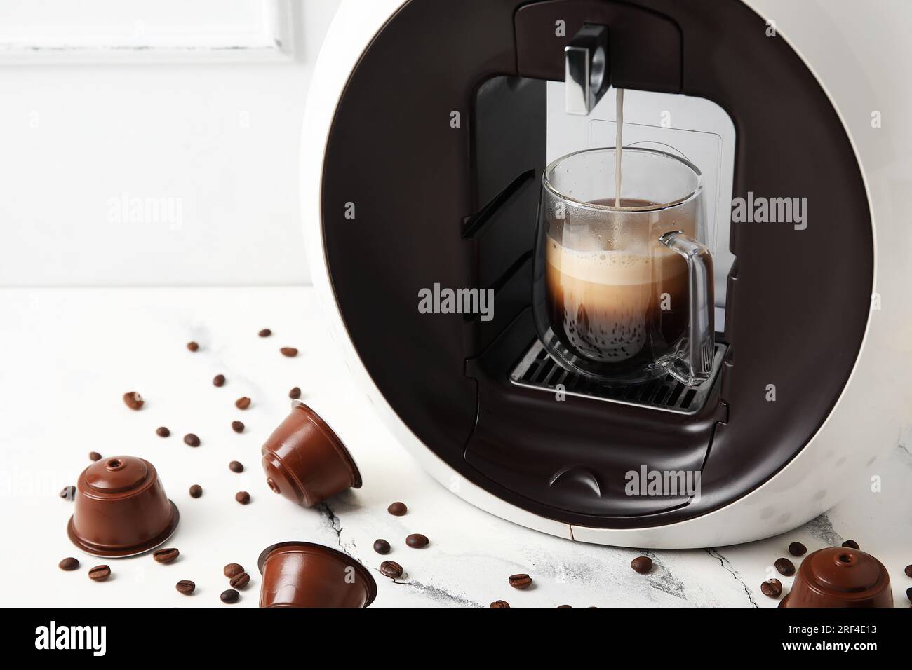 Moderna cafetera de cápsulas con goteo de espresso, taza, vainas y granos  en mesa grunge gris Fotografía de stock - Alamy