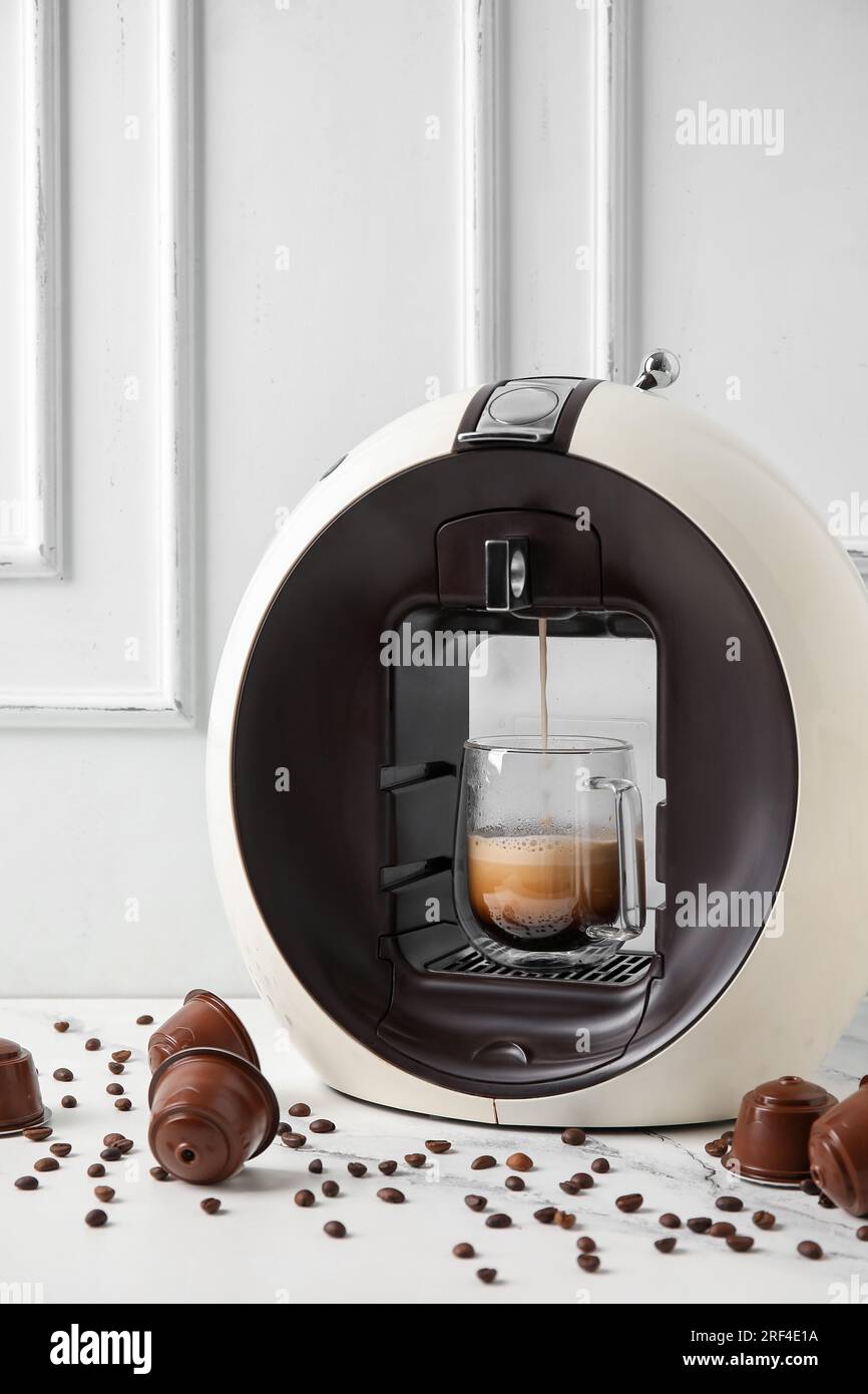 Moderna cafetera de cápsulas con goteo de espresso, taza, vainas y granos  en mesa grunge gris Fotografía de stock - Alamy