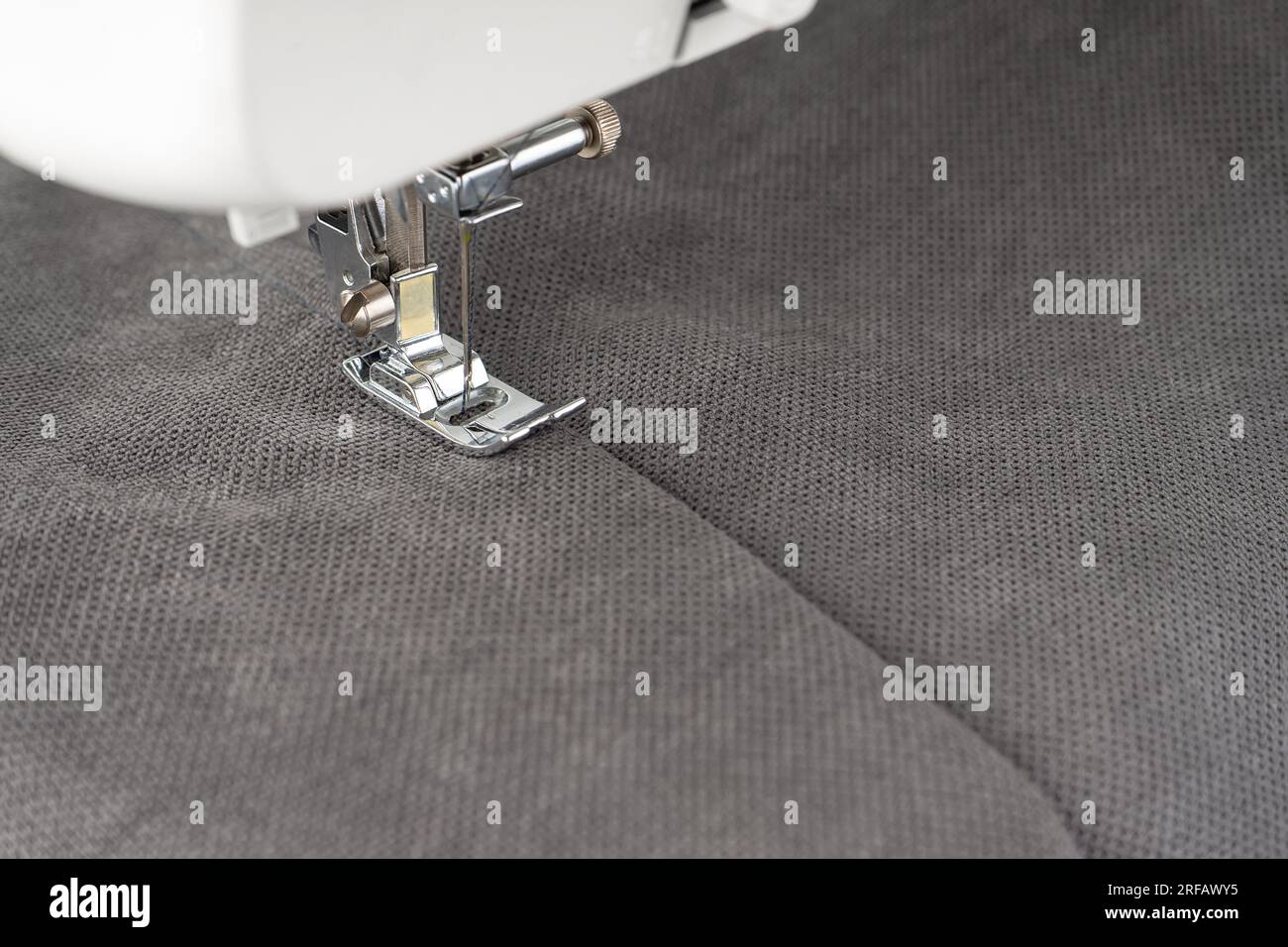 Máquina de coser moderna con tela gris y. Proceso de costura ropa, cortinas, tapicería. Negocio, hobby, hecho a mano, cero residuos, reciclaje, reparar con Foto de stock