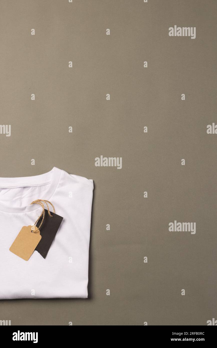 Camiseta blanca doblada con etiquetas con espacio de copia sobre fondo marrón Foto de stock