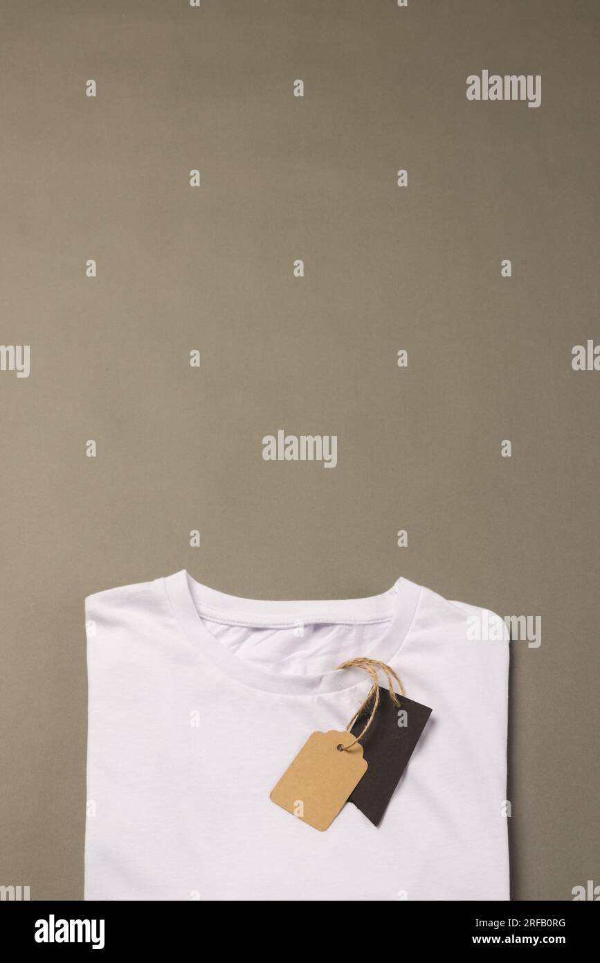 Camiseta blanca doblada con etiquetas con espacio de copia sobre fondo marrón Foto de stock