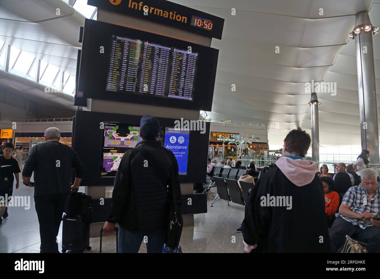 Aeropuerto de Londres Heathrow Terminal de Inglaterra Dos pasajeros que miran a la tabla de salidas Foto de stock
