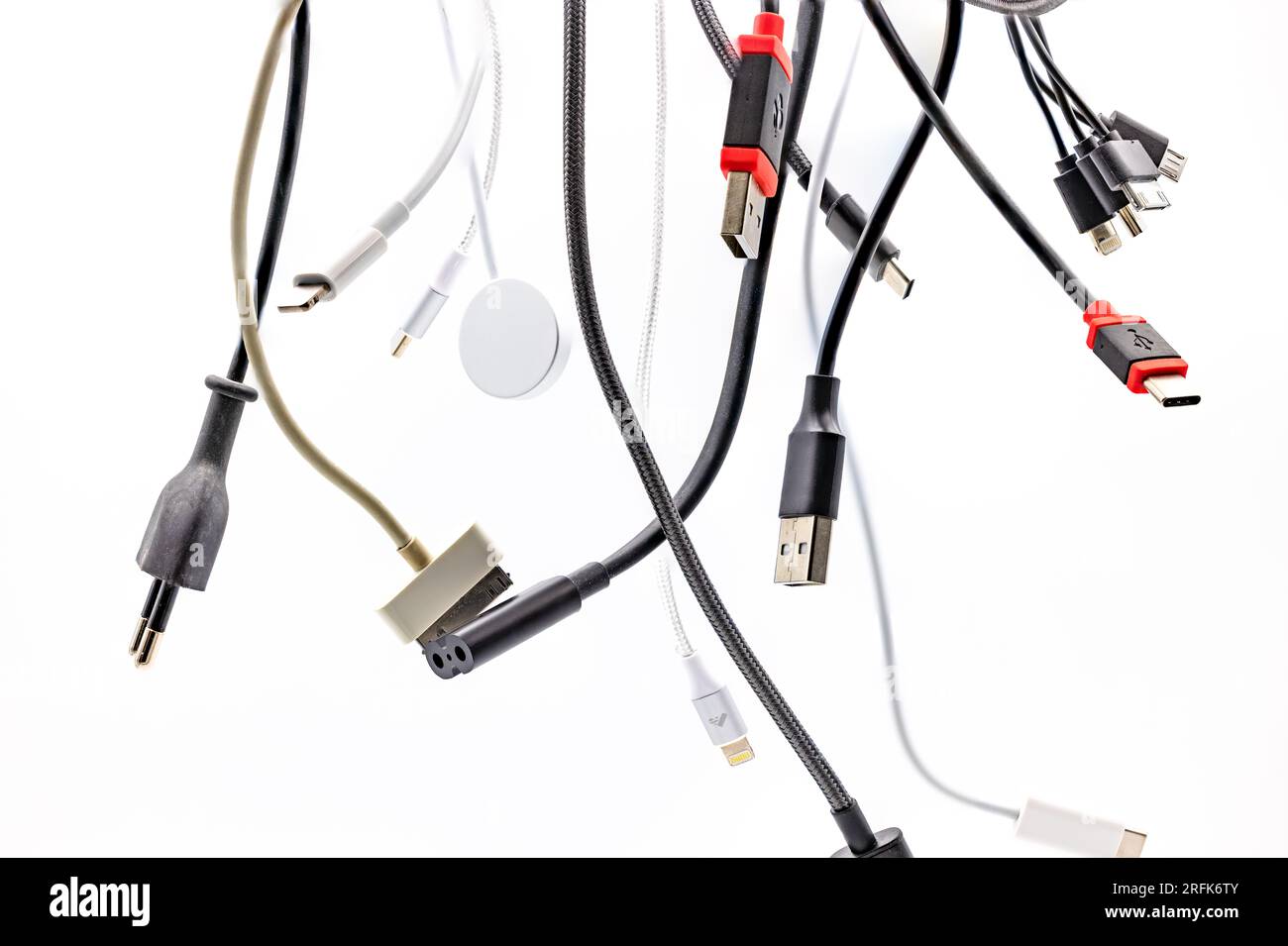 Caos y confusión con enchufes, zócalos y cables USB aislados contra un fondo blanco con apilamiento de enfoque Foto de stock