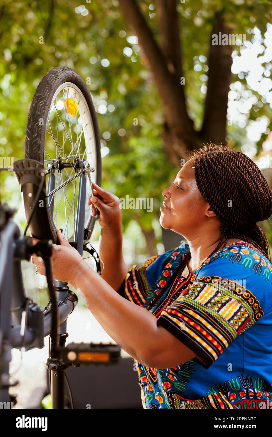 Joven ciclista activa sujetando una llave para apretar tornillos y reparar  piezas de bicicleta en el exterior. Mujer afroamericana entusiasta  deportiva que sostiene la herramienta profesional para el mantenimiento de  la bici
