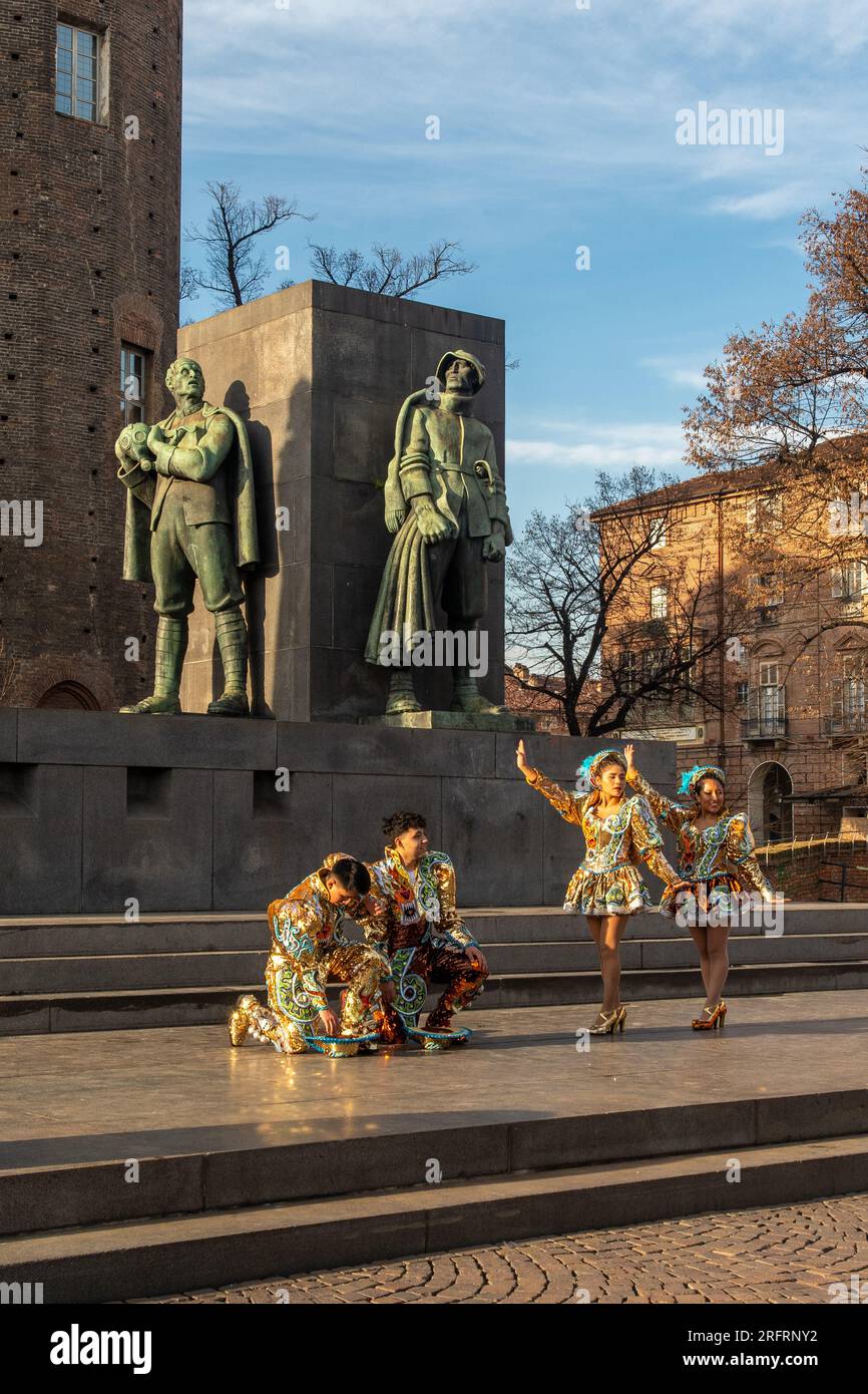 Bailarines bolivianos con trajes tradicionales en Piazza Castello frente al monumento al duque de Aosta (1937), Turín, Piamonte, Italia Foto de stock