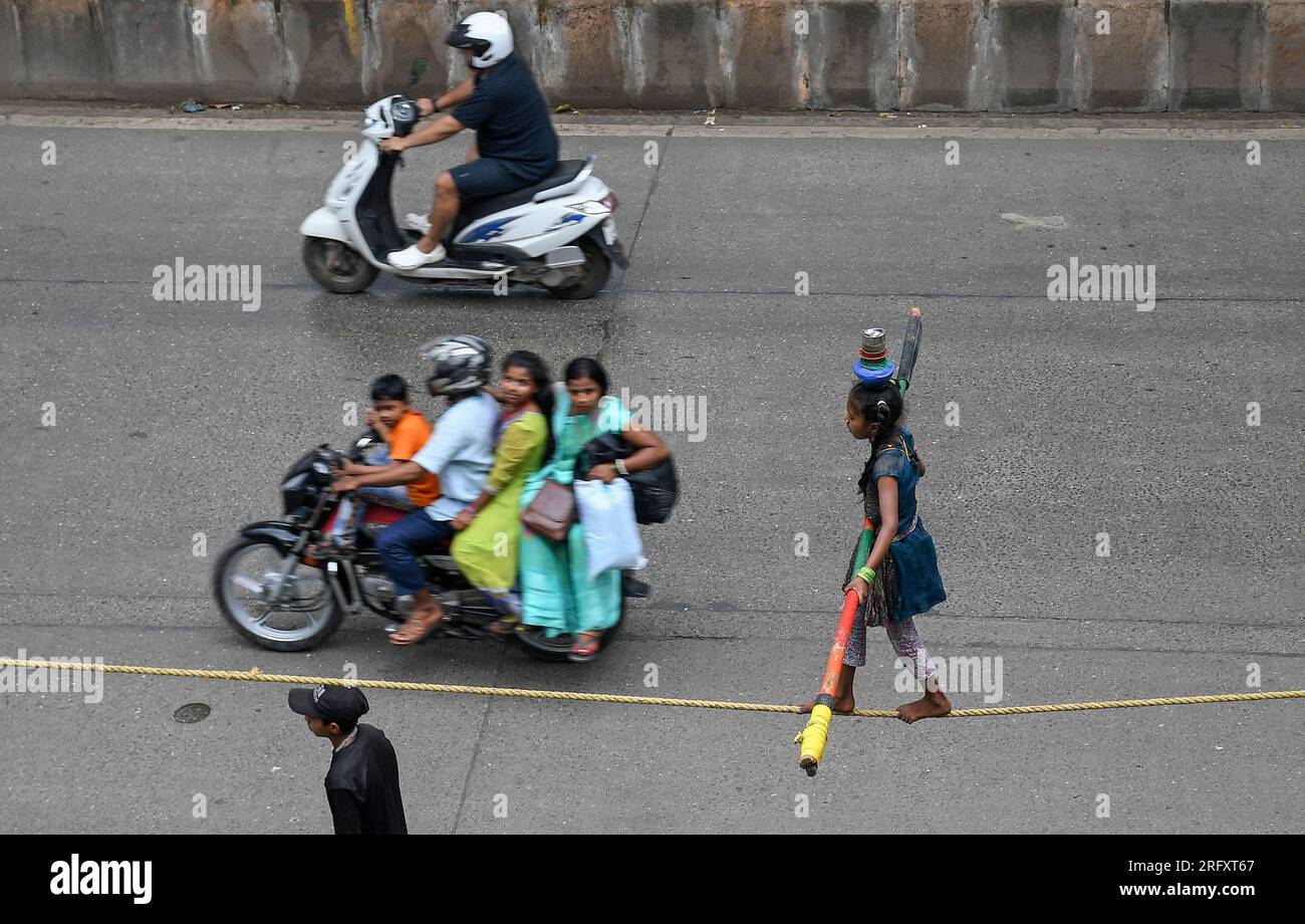 Mumbai, India. 06 de agosto de 2023. Una niña sosteniendo un palo de bambú para equilibrarse realiza un paseo por la cuerda floja en la calle de Mumbai. Los caminantes de cuerda floja se ganan su sustento actuando en las calles dependiendo principalmente del dinero dado por la gente que observa su acto de riesgo. (Foto por Ashish Vaishnav/SOPA Images/Sipa USA) Crédito: SIPA USA/Alamy Live News Crédito: SIPA USA/Alamy Live News Foto de stock