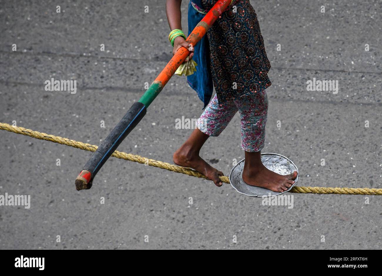 Mumbai, India. 06 de agosto de 2023. Una niña sosteniendo un palo de bambú y un plato de metal para equilibrarse realiza un paseo por la cuerda floja en la calle de Mumbai. Los caminantes de cuerda floja se ganan su sustento actuando en las calles dependiendo principalmente del dinero dado por la gente que observa su acto de riesgo. (Foto por Ashish Vaishnav/SOPA Images/Sipa USA) Crédito: SIPA USA/Alamy Live News Crédito: SIPA USA/Alamy Live News Foto de stock
