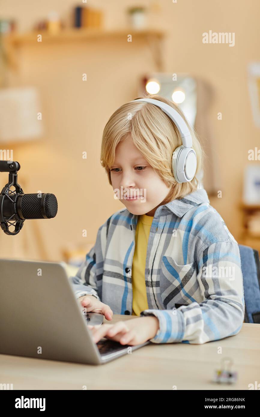 Sonriente lindo colegiala en auriculares mirando la pantalla del