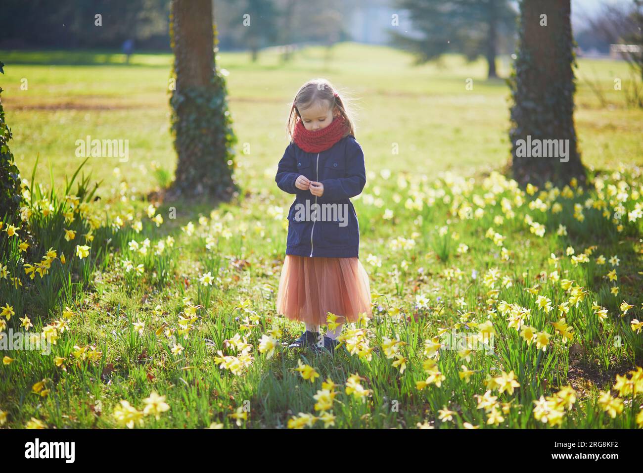 Adorable niña disfrutando de agradable y soleado día de primavera en el parque. Actividades de primavera al aire libre para niños Foto de stock