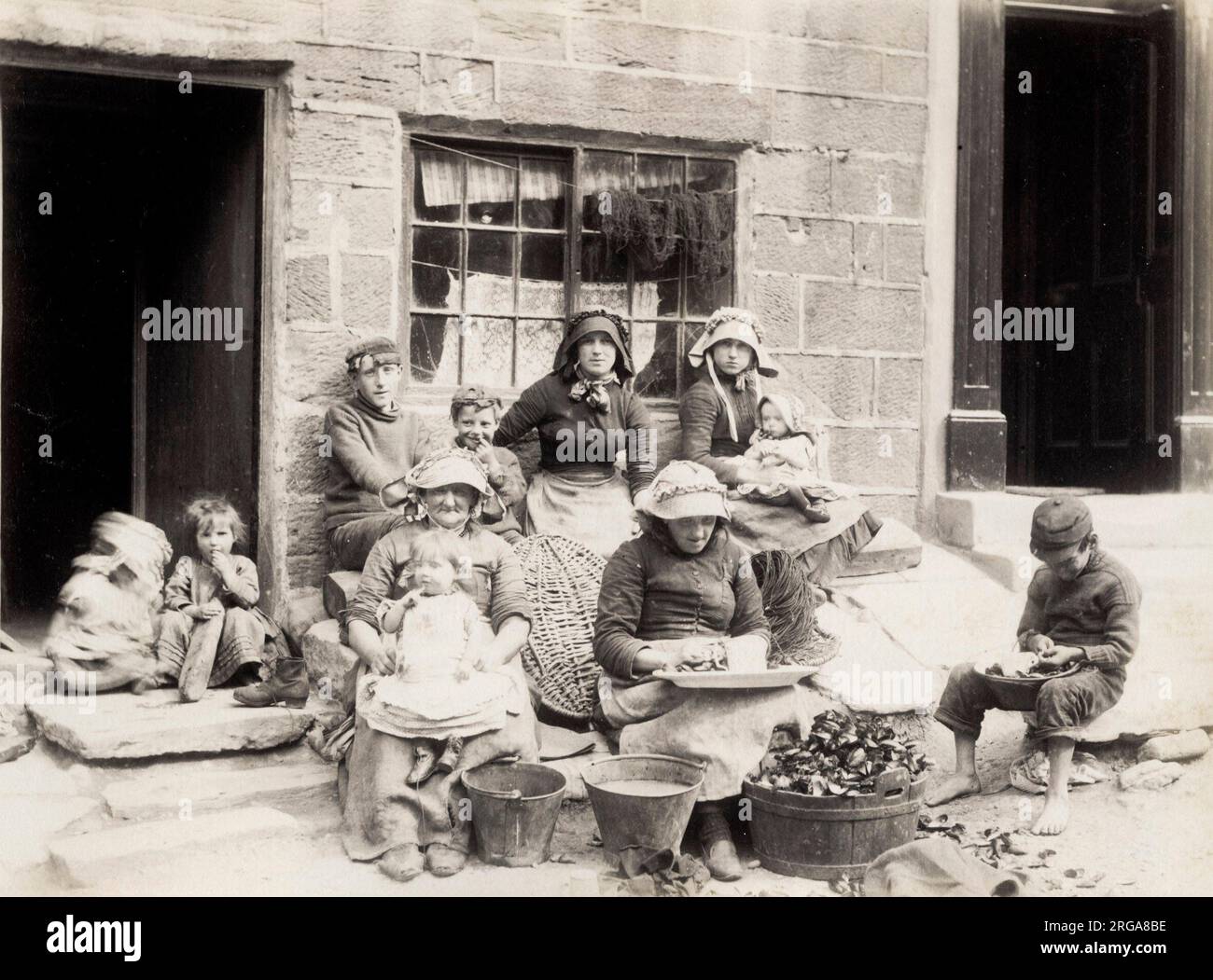 Familia pesquera fuera de su casa en Staithes Yorkshire. Fotografía vintage del siglo 19th Foto de stock