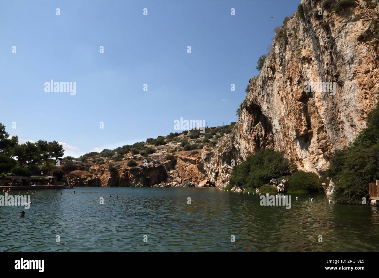 Vouliagmeni Atenas Grecia Turistas Nadar en el lago Vouliagmeni un spa natural - fue una vez una cueva, pero el techo de la cueva cayó causado por la erosión de la Foto de stock