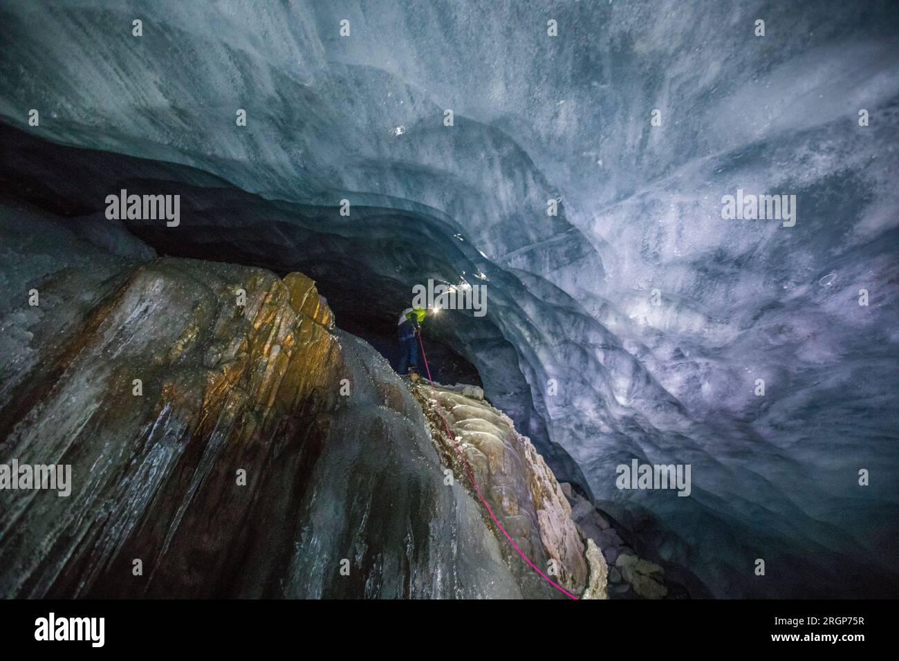 vista de ángulo bajo del escalador de hielo descendiendo en rappel por una cascada congelada Foto de stock