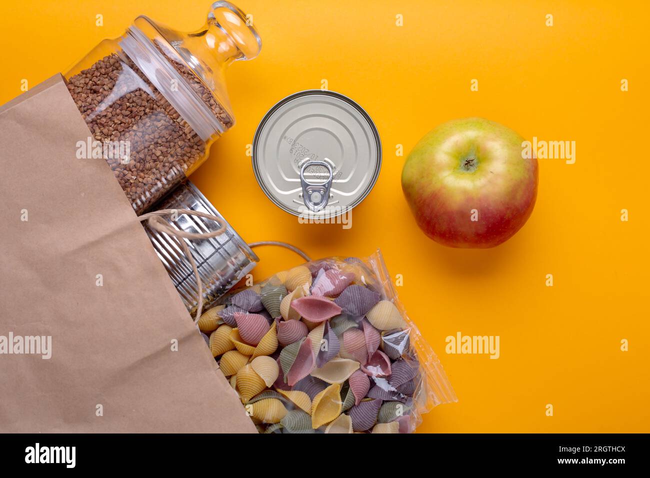 Donaciones de alimentos con comida enlatada sobre fondo de mesa amarillo Foto de stock