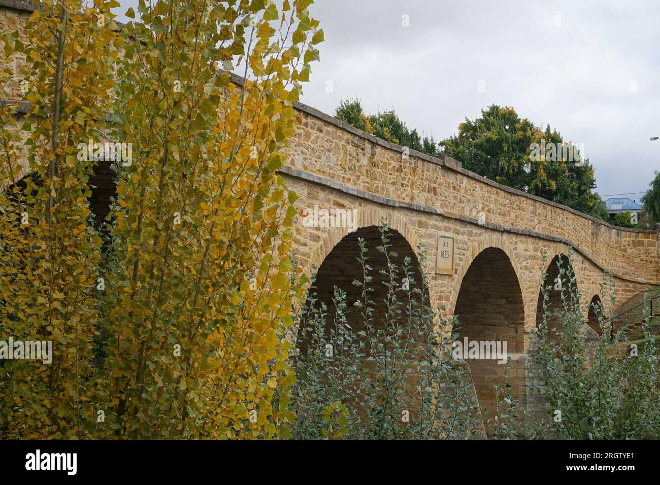 El histórico puente arqueado de Richmond en Richmond, Tasmania, Australia, con árboles de colores otoñales Foto de stock